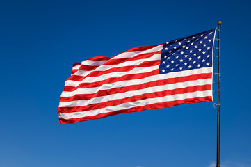 USA flag waving in the wind against a cloudless blue sky
