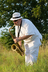 Man playing jazz on saxophone in the spring nature on a sunny day