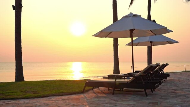 Sunbeds and Parasols on Beachfront of Tropical Sea and Evening Sunlight
