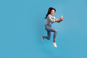 Fototapeta premium Photo of excited lady dressed shirt reading modern device jumping high smiling isolated blue color background