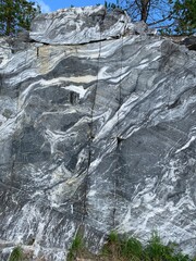 Marble rock wall in an Italian quarry with a trees on top of it