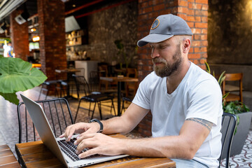 Man in casual clothes working on laptop in cafe or coworking. Typing on keyboard. Remote office...