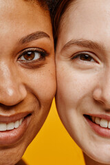 Half face closeup of two young women black and Caucasian smiling happily at camera
