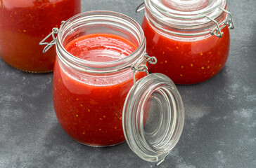 Tomato sauce in glass jars on dark background