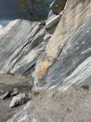 Marble rock wall in an Italian quarry with a trees on top of it