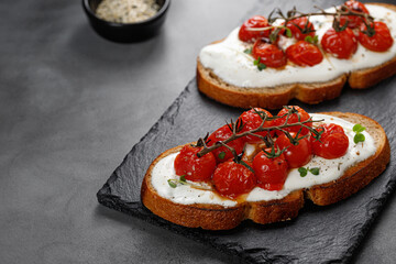 Snack, sandwiches with ricotta cheese, cream cheese and baked tomatoes cherry on white plate. Healthy vegetarian toast with whole grain bread.