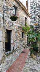 Fototapeta na wymiar Eze, France, October 2, 2021: Stone exterior of old buildings on narrow streets in the picturesque medieval city of Eze Village in the South of France, along the Mediterranean Sea.