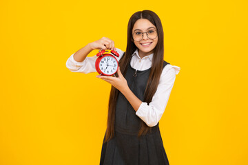 Child student girl with clock isolated on yellow background. Child back to school. Education and time concept. Happy girl face, positive and smiling emotions.