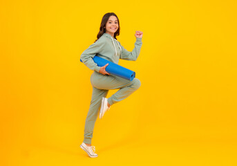 Fototapeta na wymiar Run and jump. Girl teenager in tracksuit. Happy cute child in a yellow sports suit on a yellow background. Sportswear advertising concept.