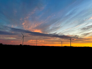 Obraz premium Orange sunset with purple cloud in the landscape, black silhouette of the windmills