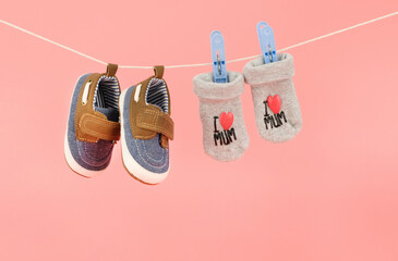 Hanging baby shoes and socks isolated on pink background, baby clothing concept