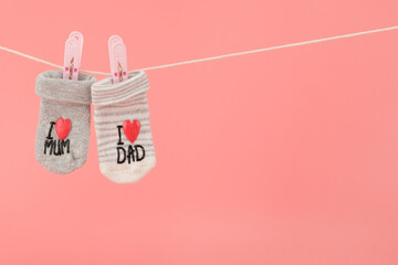 Hanging baby socks isolated on pink background, baby clothing concept