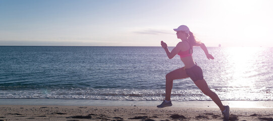 Woman run and jump on sea beach. Energetic running woman in activewear run on beach sand along...