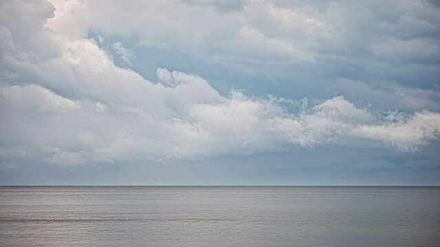 Amazing blue cloudscape with clouds forming over a calm sea. Tranquil timelapse.