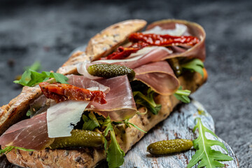 prosciutto sandwich, Ciabatta with prosciutto, sun-dried tomatoes, gherkins, parmesan and arugula,...