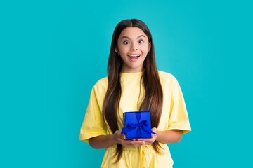 Child with gift present box on isolated studio background. Gifting for kids birthday. Excited face, cheerful emotions of teenager girl.