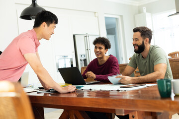 Smiling male entrepreneur discussing with male coworkers working at desk in office, copy space