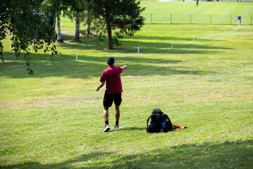 Disc golf player throwing a disc golf on a sunny summer day.