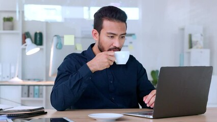 Happy young male office manager working on his computer at his job. A confident business man drinking his coffee at a desk. Smiling employee reading his email online at work.