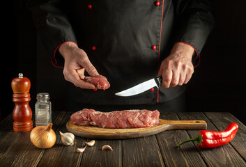 Butcher or chef cuts beef raw meat on a cutting board before barbecue. Preparing a delicious meal in the kitchen
