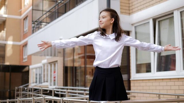 A preteen girl is dancing in front of the entrance to the school.