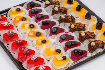 Tray with mini cakes with fresh blueberries, blackberries and raspberries