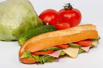 sandwich with ham, cheese and fresh tomatoes, cucumbers and lettuce leave on white background