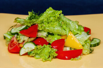 Healthy organic salad of fresh vegetables: bell peppers, tomatoes, cucumbers with lettuce leaves
