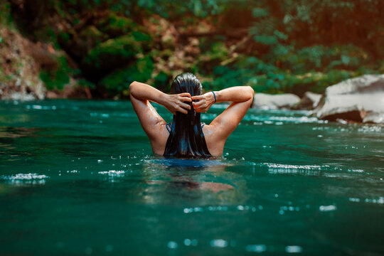 young Latina woman swimming in Rio Fortuna in Costa Rica with totally wet long hair