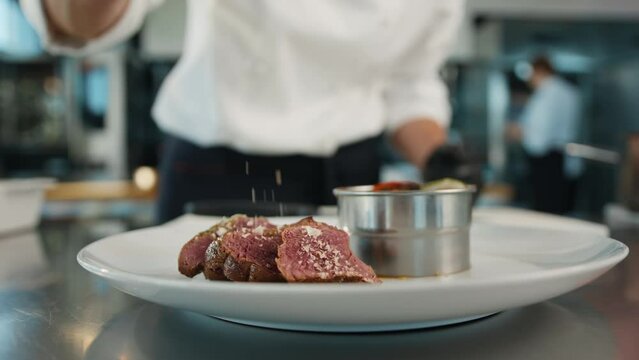 The chef sprinkles the filet mignon with coarse salt. Serving food in a restaurant.