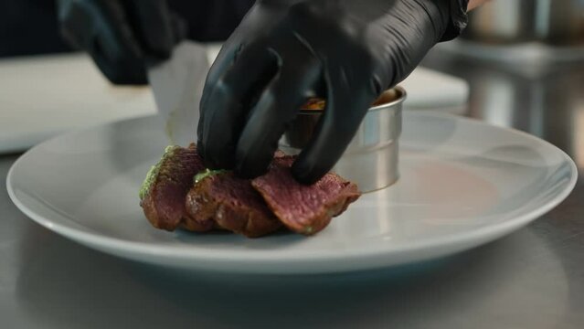 The chef puts filet mignon on a plate with ratatouille. Serving food in a restaurant.