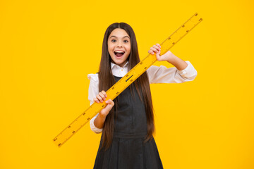 Fototapeta na wymiar School girl holding measure for geometry lesson, isolated on yellow background. Measuring equipment. Student study math. Excited face, cheerful emotions of teenager girl.