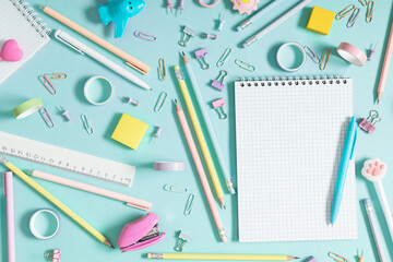 Back to school background. Flat lay, top view of colorful scattered stationery on isolated pastel blue table background. School supplies on desk. Copyspace.