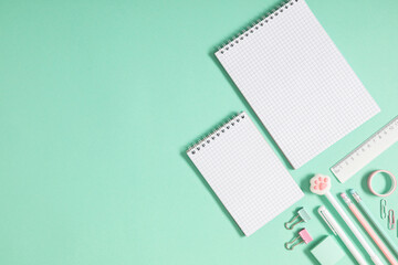 Back to school background. Flat lay, top view of colorful scattered stationery on isolated pastel light green table background. School supplies on desk. Copyspace.