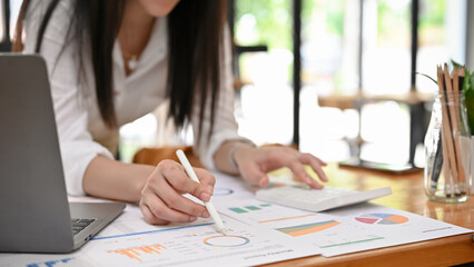 Cropped, Professional Asian businesswoman analysing and working on the report.