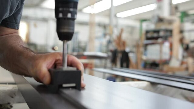 Carpentiere che fa un foro con trapano su una tavola di legno