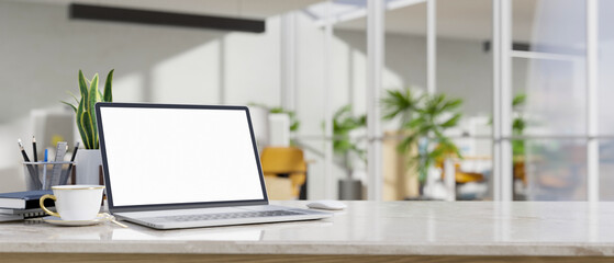 Modern white working table with laptop mockup and copy space over blurred office background.