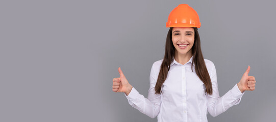 happy woman in protective helmet and white shirt showing thumb up gesture, good result. Woman...
