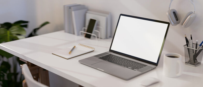Modern white office desk with laptop mockup and office accessories. close-up image.