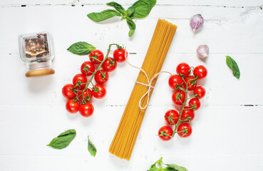 Spaghetti, basil and tomatoes isolated on white wooden table. Top view