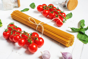 Spaghetti, basil and tomatoes isolated on white wooden table.