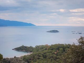 travel to Lagoon in Oludeniz, Fethiye, Turkey. beach near Darbogaz. Winter landscape with mountains, green forest, azure water, beach and cloudy sky