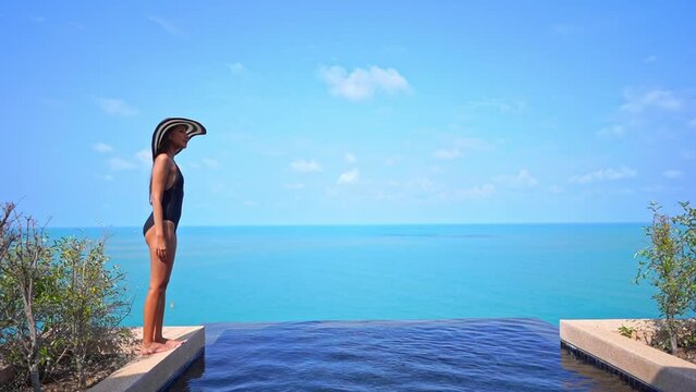 Slender Woman in Swimsuit Standing by Infinity Pool of Private Villa With Amazing View of Tropical Sea