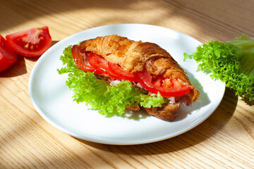 Croissant sandwich with mozzarella, tomatoes and basil. Italian breakfast. Tasty food