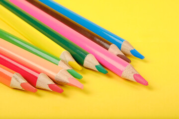 Multi-colored pencils isolated on yellow background closeup.