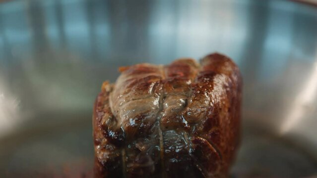 Close-up of a filet mignon being cooked in a frying pan