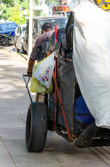 homeless man carrying garbage sacks on a cart