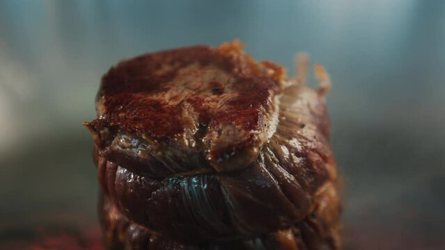 Close-up of a raw filet mignon being cooked in a frying pan