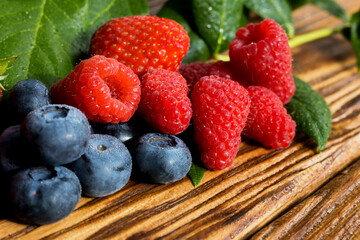 Berries on a wooden background. Summer or spring Organic berry. Strawberries, Raspberries, Blueberries. Agriculture, Gardening, Harvesting Concept.