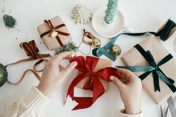 Merry Christmas! Hands wrapping stylish christmas gift flat lay. Person preparing  christmas...